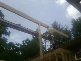 Carpenter setting a ridge beam over a new addition frame — Ice Dam Removal by Roofing Brothers in Kaw City