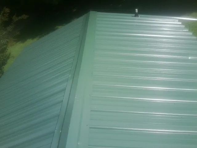 New green metal panels meeting at the ridge of a roof — Flat Roof Repair work by our crew in Kaw City