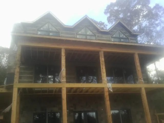 Dormers and porch framing on a large log home under construction — Roof Coating work by our crew in Kaw City