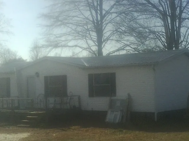 New metal roof on a white painted brick home on a foggy morning in Kaw City
