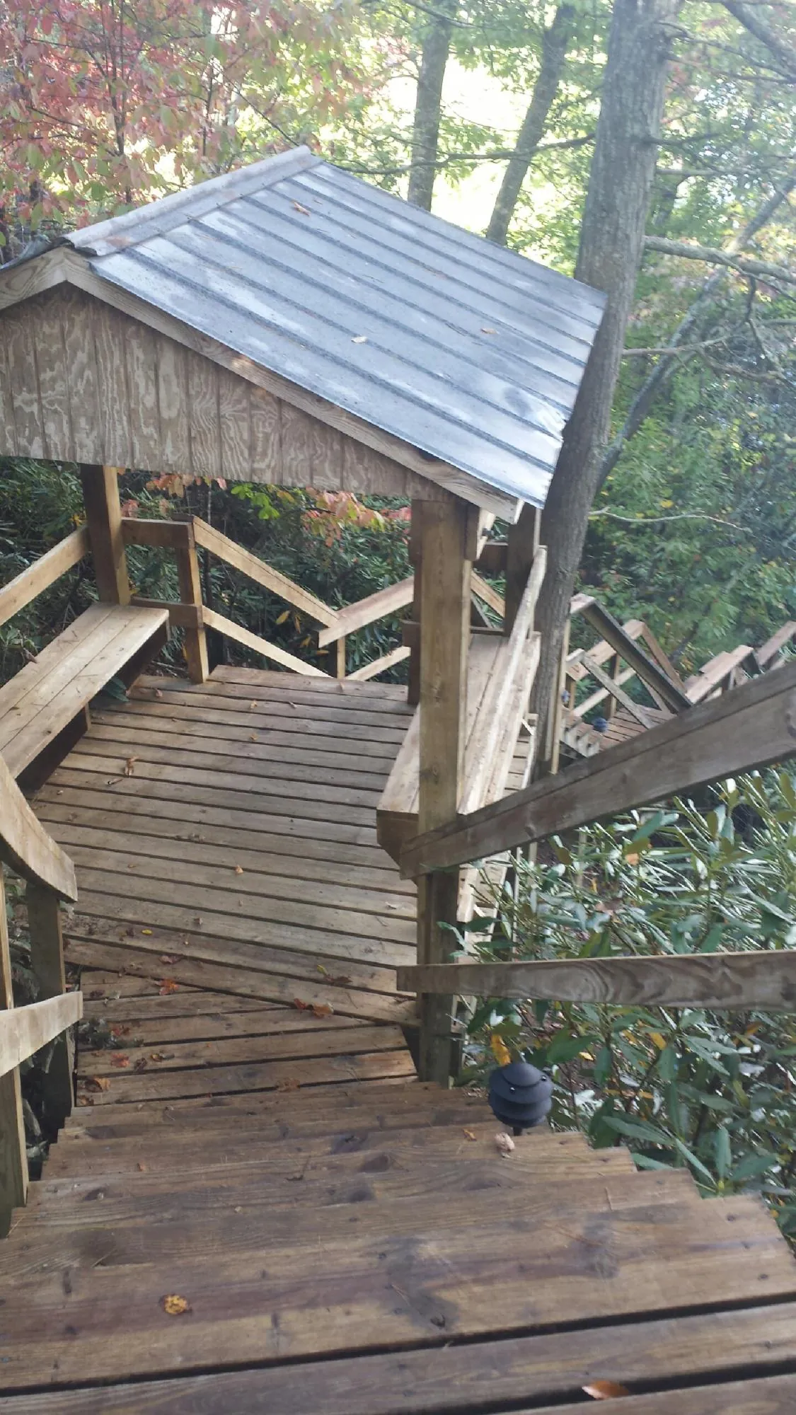 Metal roofed shelter over wooden steps on a wooded walkway — Skylight Repair & Installation work by our crew in Kaw City