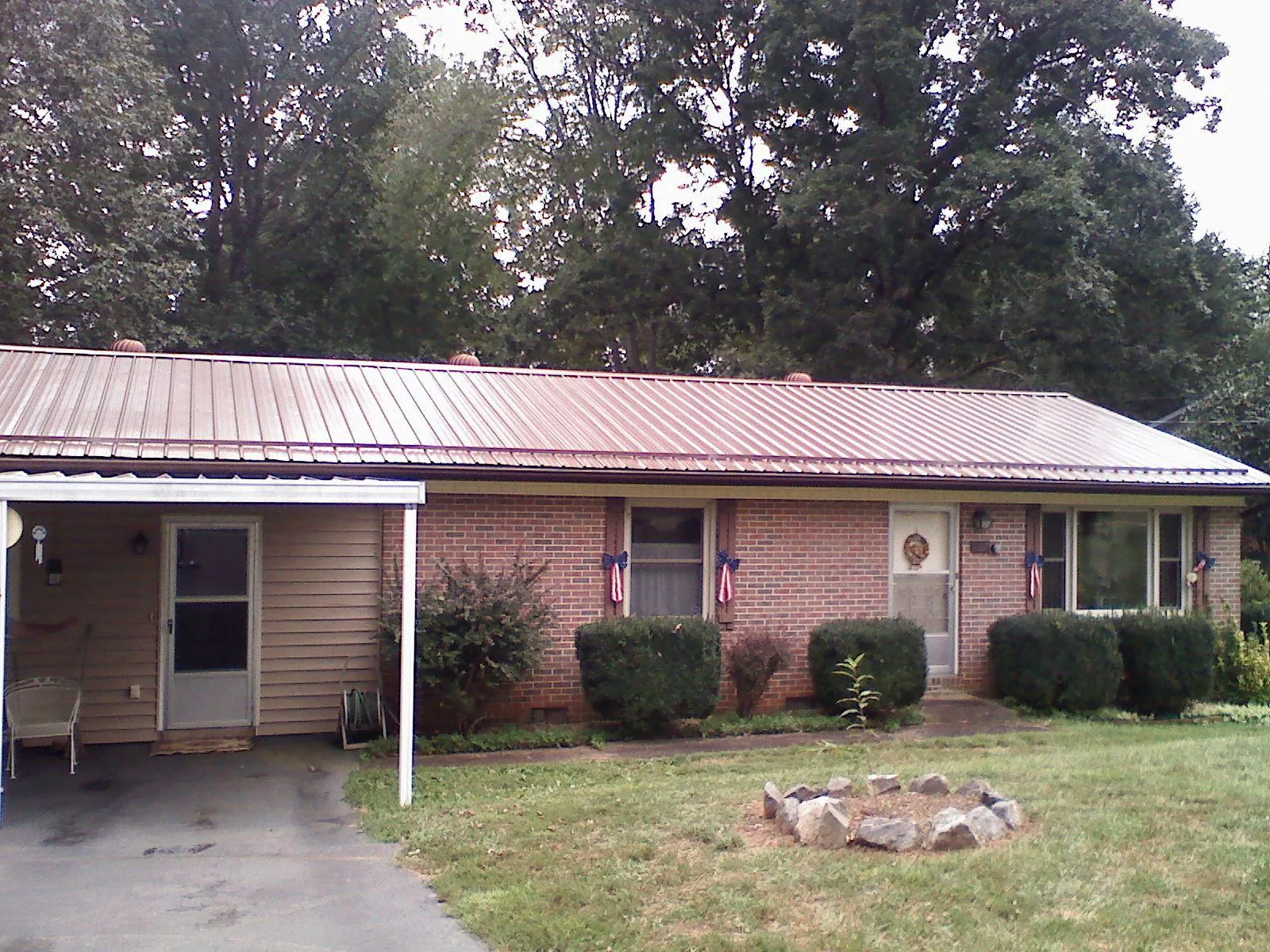 Bronze metal roof and carport on a brick ranch home — Roof Repair work by our crew in Kaw City