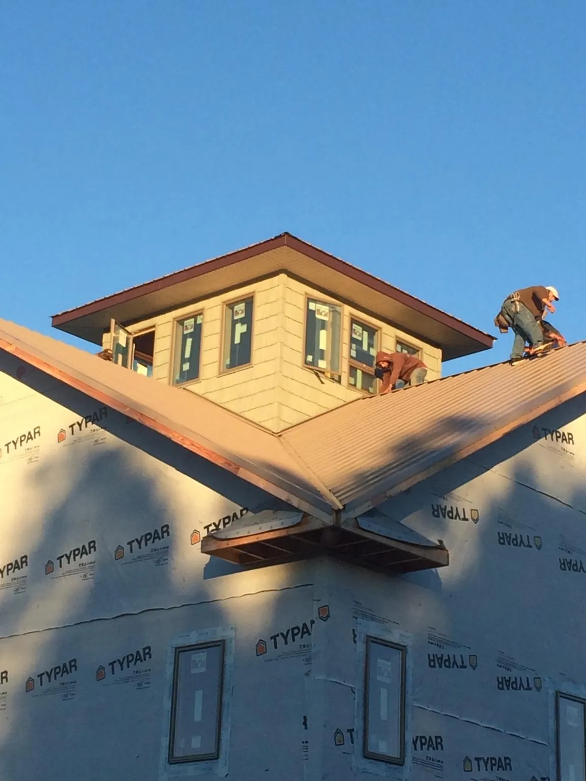 Roofers working around a rooftop cupola on a new metal roof at sunset — Roof Waterproofing in Kaw City by Roofing Brothers